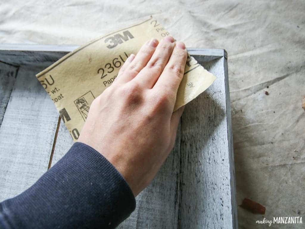 Woman hand distressing the farmhouse style wood tray