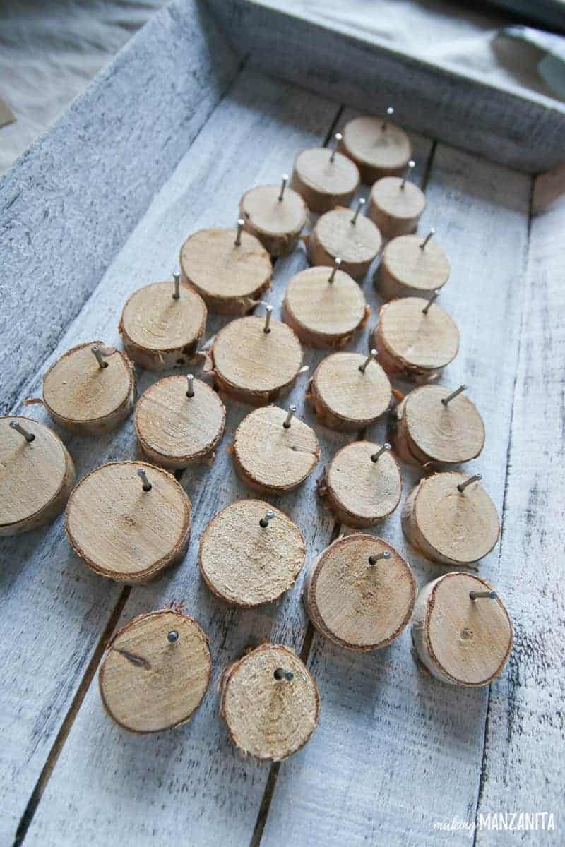 Small wood rounds nailed to a painted wood tray in the shape of a Christmas tree