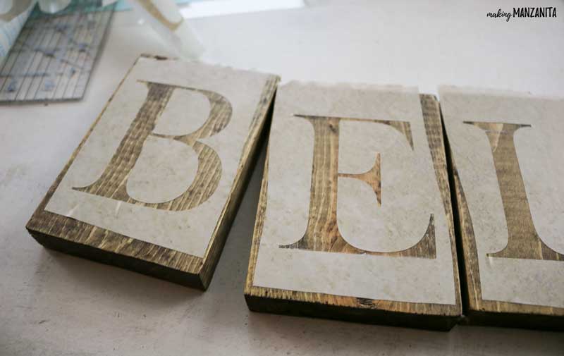 Carefully applying the letter stencils to the wooden blocks to make a DIY Christmas sign