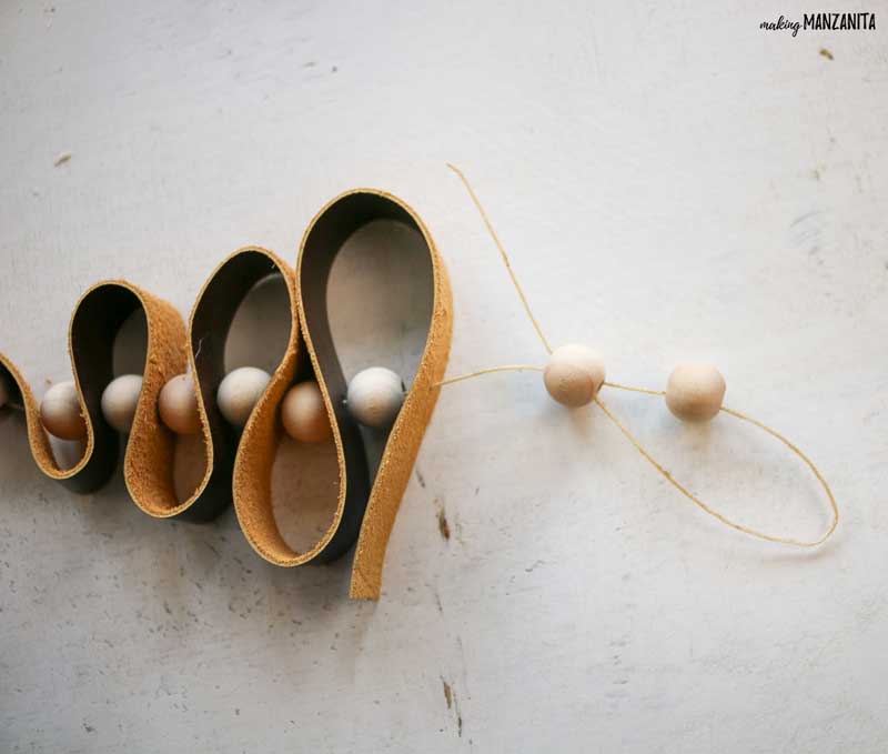 Showing wooden beads and leather on string to create leather christmas ornament