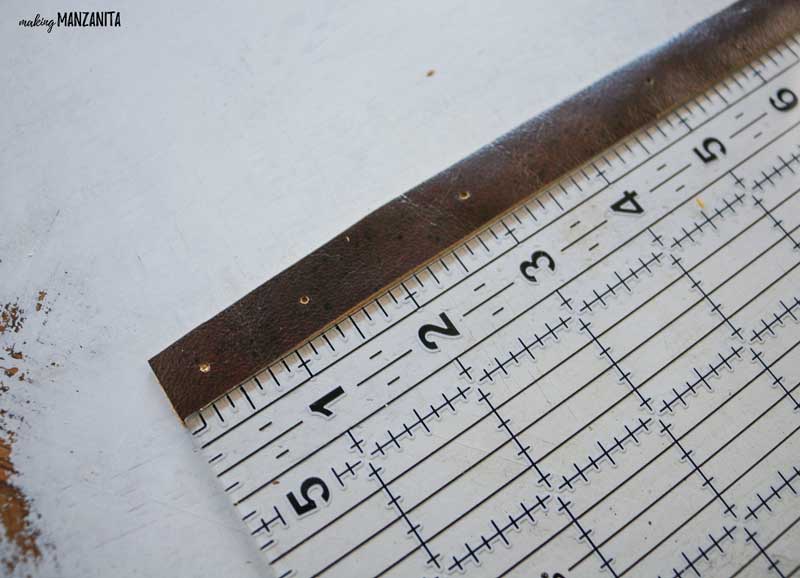 Leather strip with holes punched in it laying next to an acrylic ruler to show location of holes