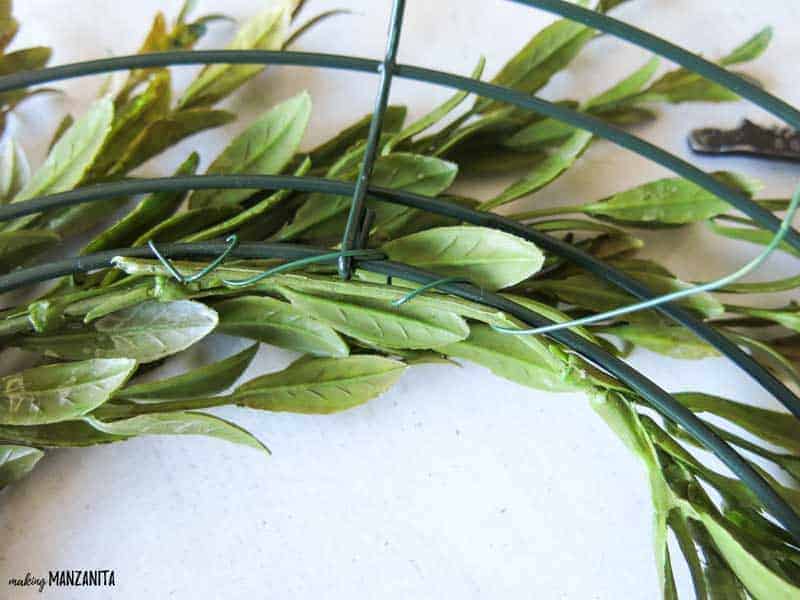 Use floral wire to attach the fauz tea leaves to the wreath frame, creating the base for your farmhouse style wreath