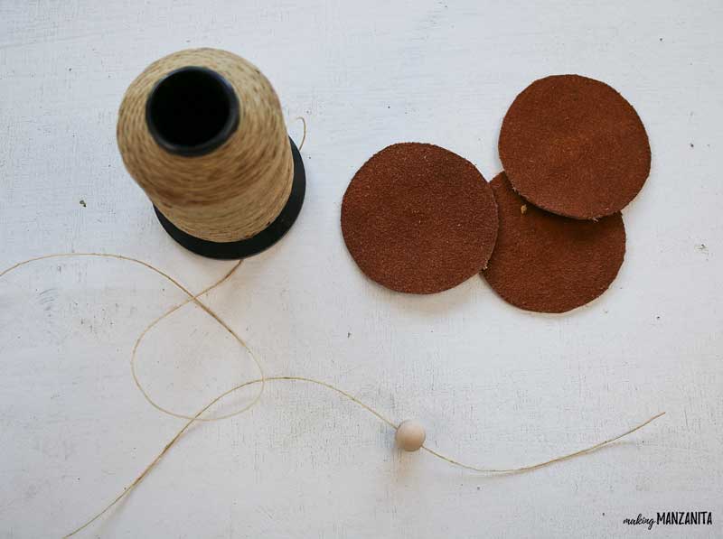 Start stringing wood beads onto twine for your DIY leather Christmas ornaments