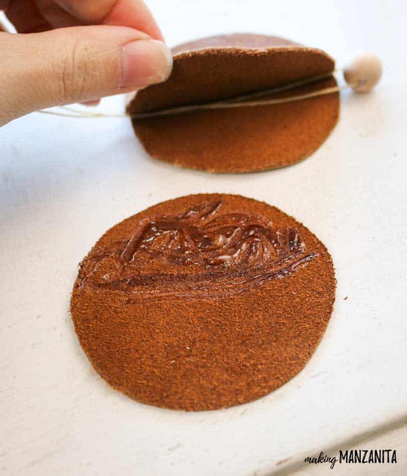 Apply craft glue to the 2 leather circles, then insert the beaded twine between the two circles