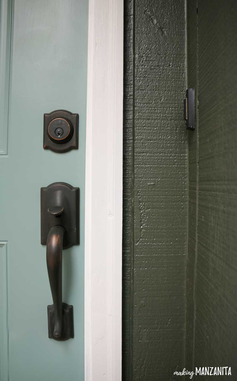 Comparing our new front door paint color with our home's exterior paint color. Our front door is painted a light mint green, and our home is painted a deep forest green. In The Moment and Bamboo Black, both by Behr.