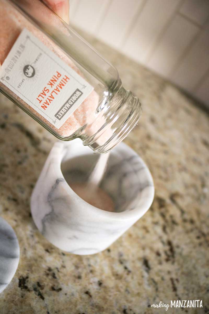 Pouring Himalayan Pink Salt into a marble salt cellar.
