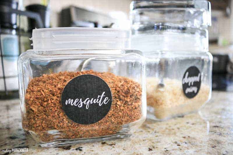 Two clearly labeled spice jars sit on the kitchen counters; these spice jars are labeled with black stickers with white text that read "mesquite" and "chopped onions".
