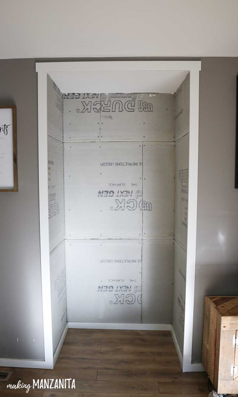 A head-on look at the empty alcove in our living room, the walls lined with incomplete construction concrete backer and wood trim.