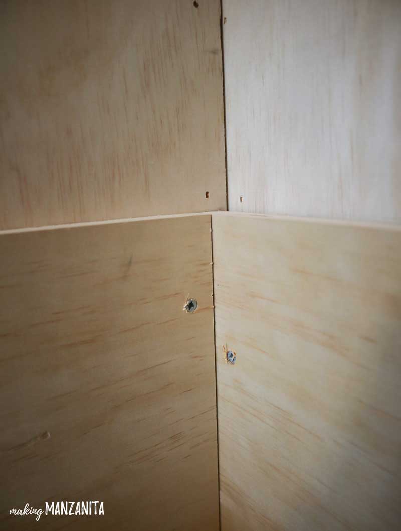 A close up look at the inner corner of the wood storage box frame, nailed into the wall of the living room alcove.