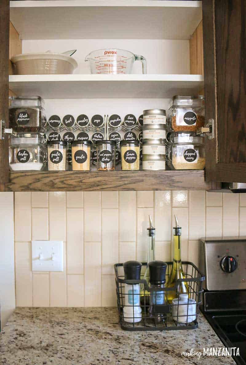 A look inside our brilliantly organized spice cabinet, organized with glass jars, spice keepers, tins, and spice bottles are clearly labeled with spice jar sticker labels made on the Silhouette Cameo.