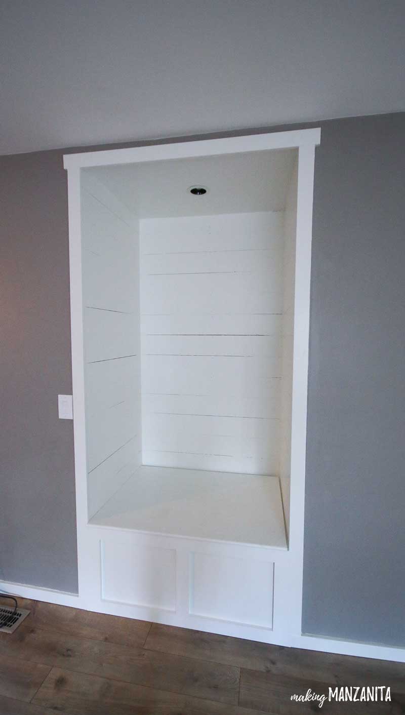 A look at our completed living room reading nook, made in an alcove in our living room - white shiplap walls with a bench for seating.