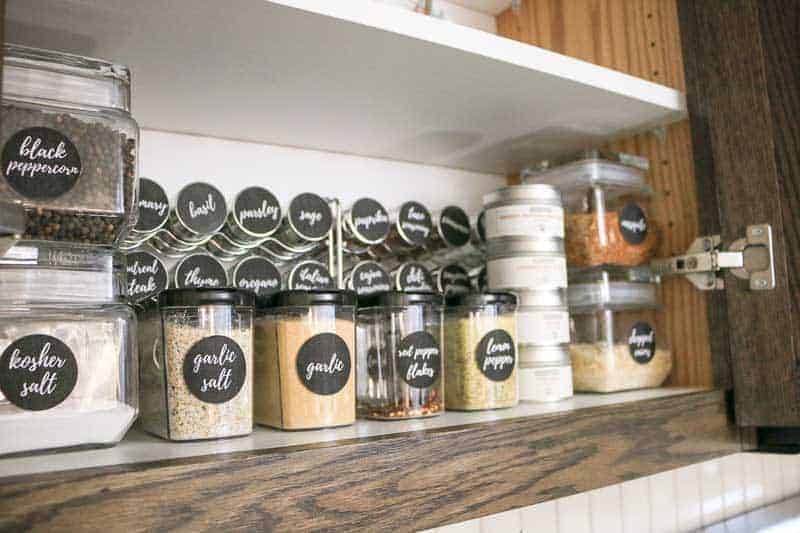 A closer look at our spice cabinet organization with neatly stacked and organized rows of spices in stackable jars, mini keepers, and small jars of clearly labeled spices.