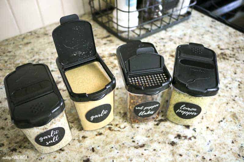 These mini spice keepers are perfect for spice cabinet organization; these four spice keepers sit on the kitchen counter, clearly labeled with stickers that read "garlic salt", "garlic", "red pepper flakes", and "lemon pepper"