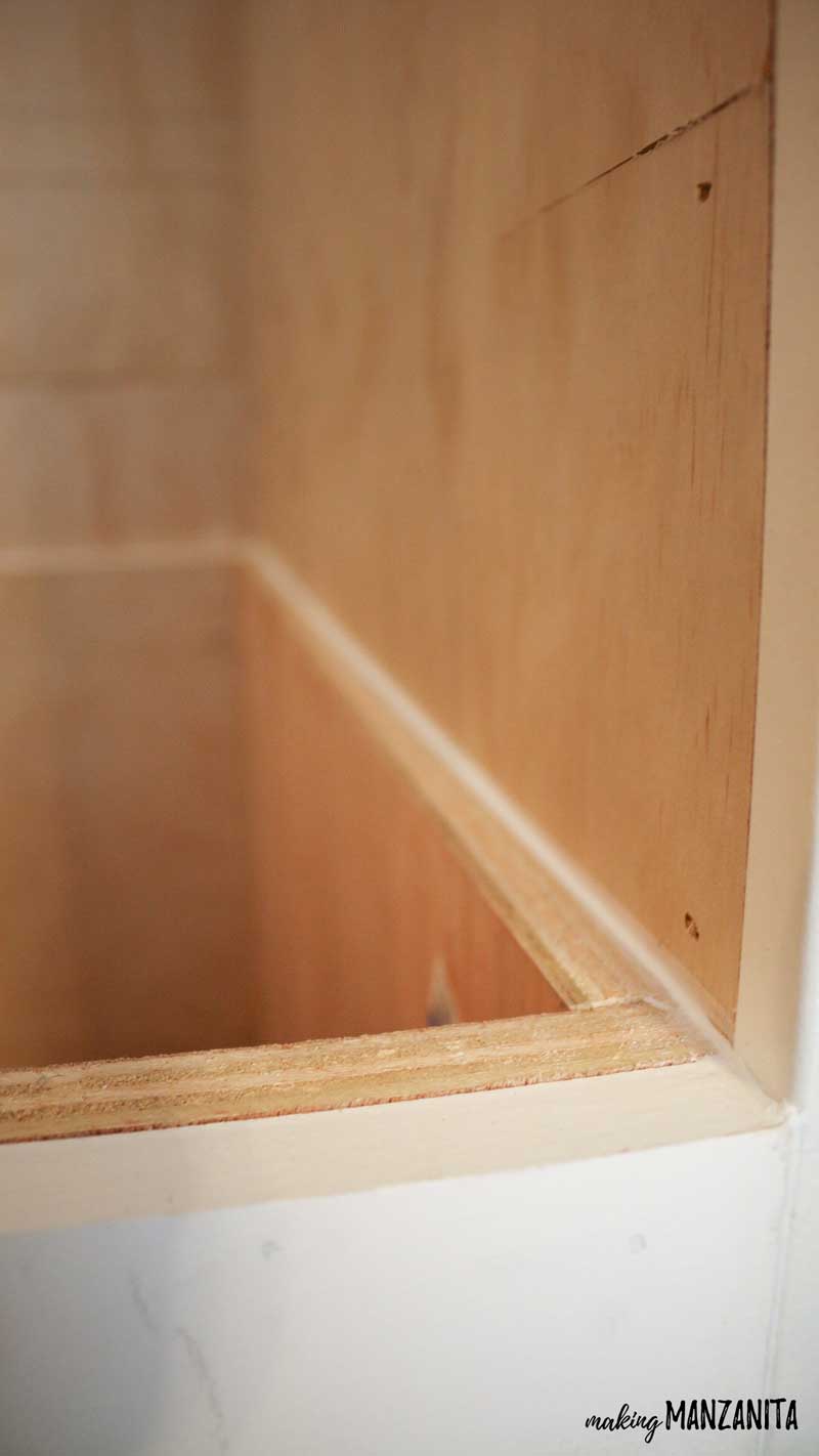 A close up look at the line of caulk that runs along the shiplap wall and top of the storage bench.