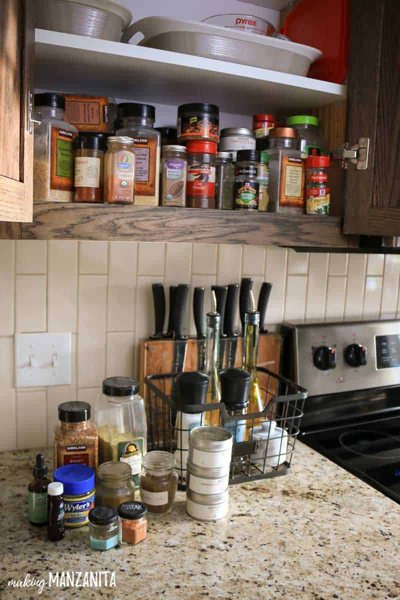 Before our spice cabinet organization project, our spice cabinet was packed with unorganized jars and bottles of spices, overflowing onto the kitchen counter.