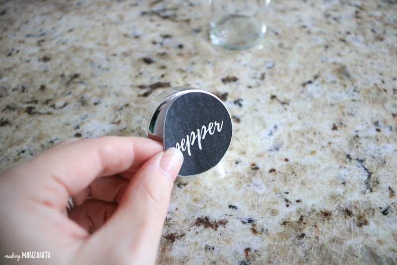 Applying a "pepper" spice jar label sticker to the lid of an empty spice jar.