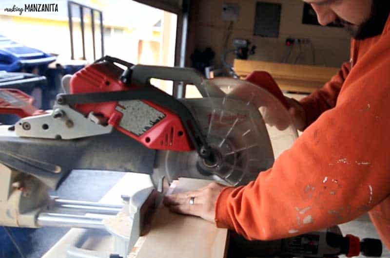 photo of a man using a miter saw to cut wood panels