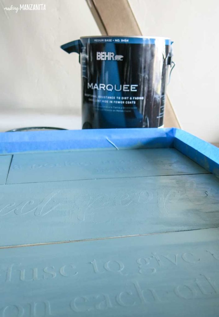 Can of Behr Marquee paint sitting next to a project taped and painted with Behr's In the Moment paint color