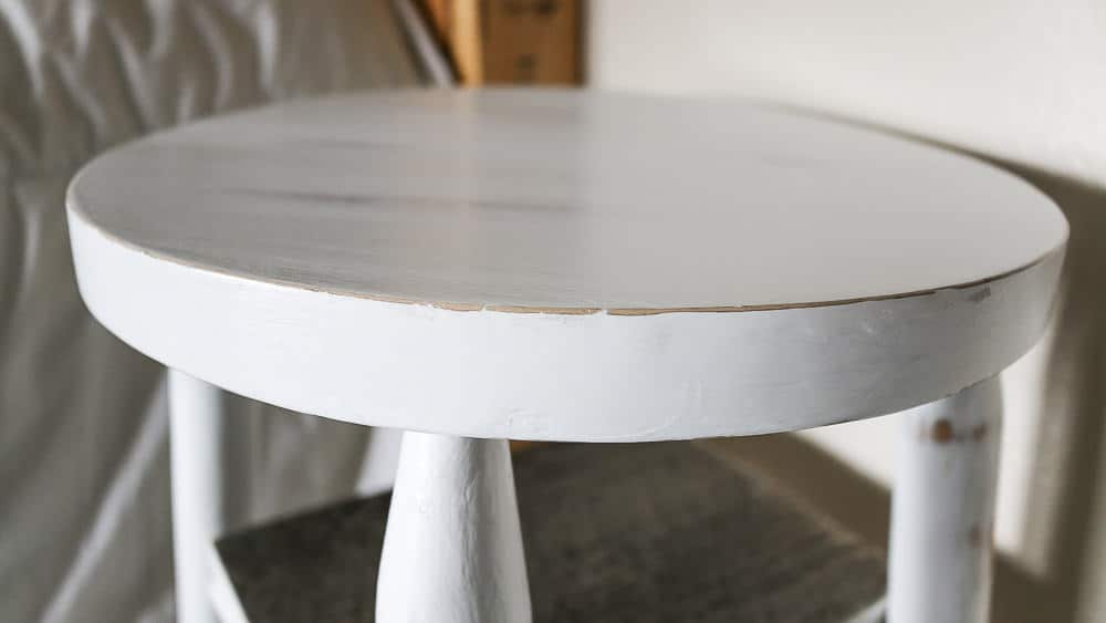 A close up look at the seat of the upcycled bar stools with chipped and distressed white chalk paint.