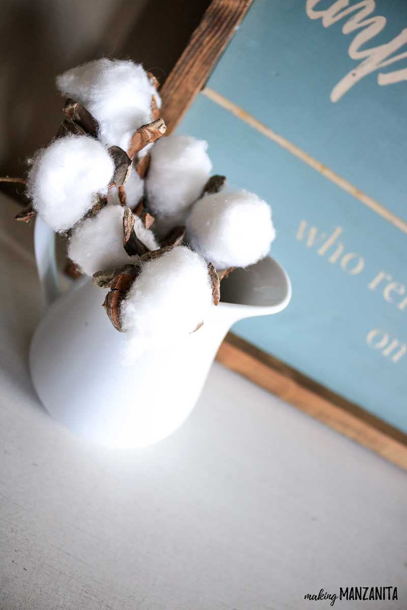This white vase filled with cotton stems is a great complement to the DIY shiplap wooden sign with quote