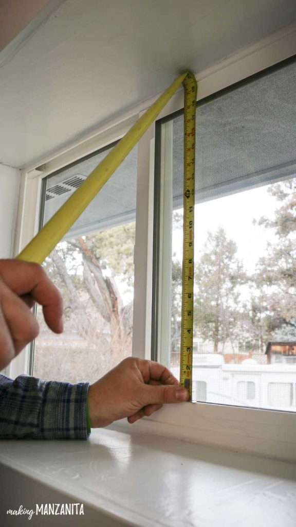 Using a measuring tape to measure the bathroom window before installing frosted bathroom window film.