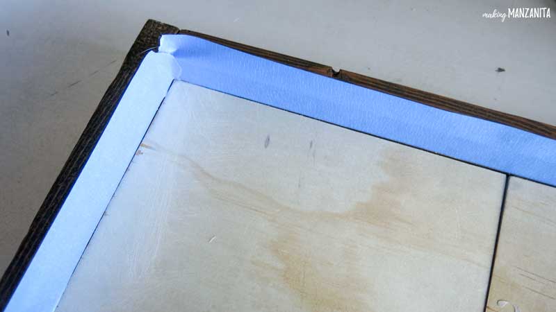 Add blue painter's tape to the inside edge of the frame of the DIY sign to prevent paint getting on the wooden frame