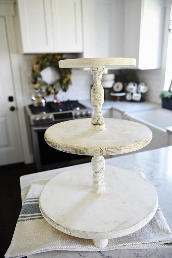 A white rustic-looking three tier wood stand that I used as inspiration for the diy three tier stand I made for my bathroom.