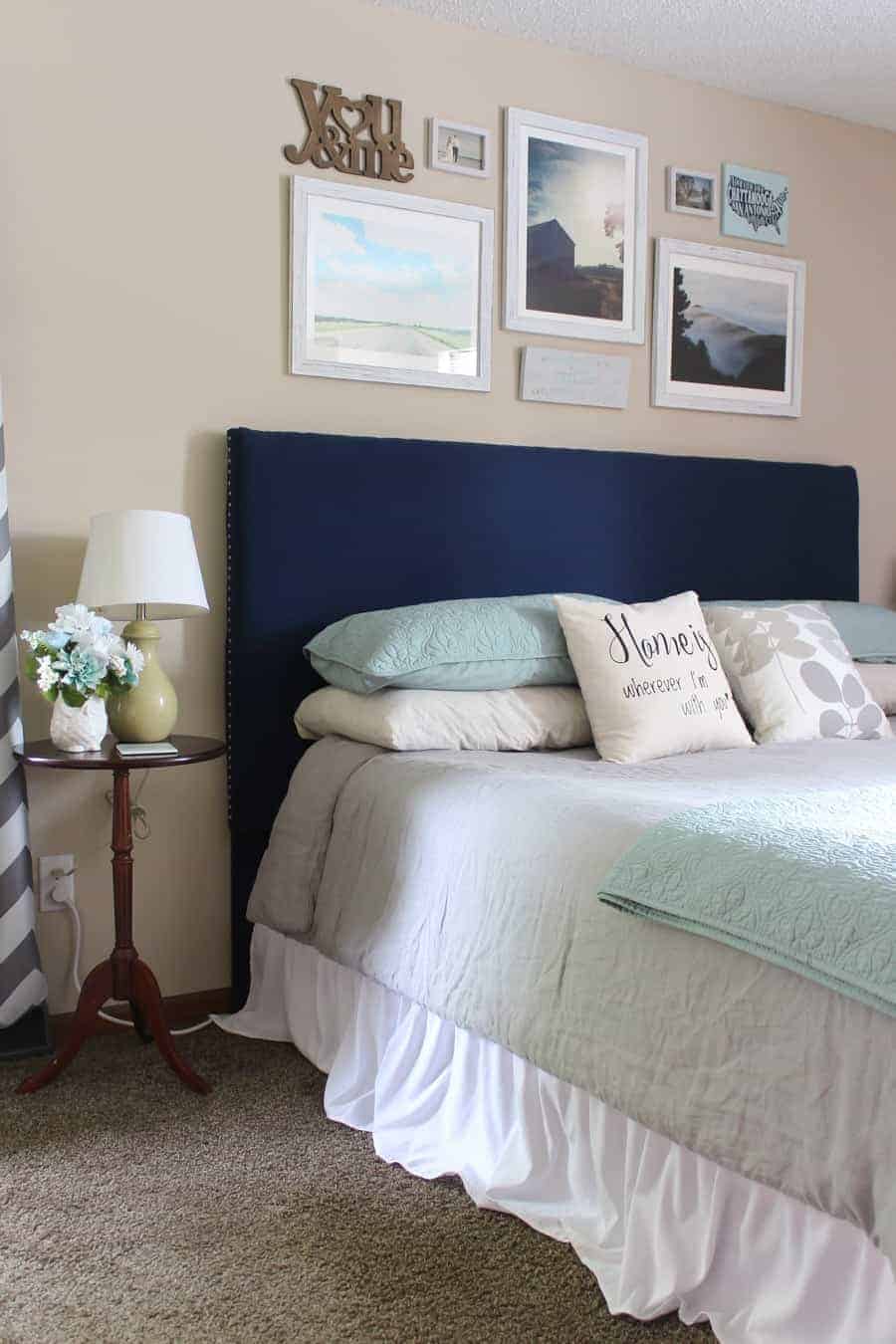 If you have tan walls in your bedroom, check out this idea with a navy headboard and gallery wall hanging for over the bed decor