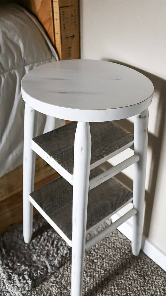 The completed upcycled bar stool - we painted the stool white and added two floating shelves to create a convenient bedside table.