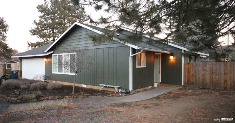 Exterior of a home with freshly painted with dark hunter green paint and white trim. Learn what types of paint sheens you should be using for exterior paint projects. 