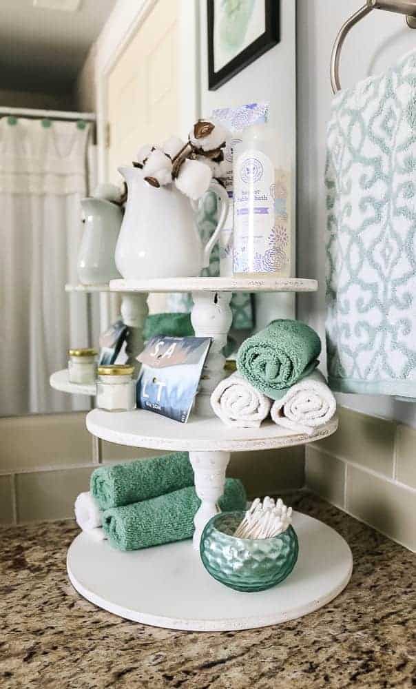 Using the white wood three tier stand in our bathroom for extra counter top storage, storing items like hand towels, toiletries, and more.