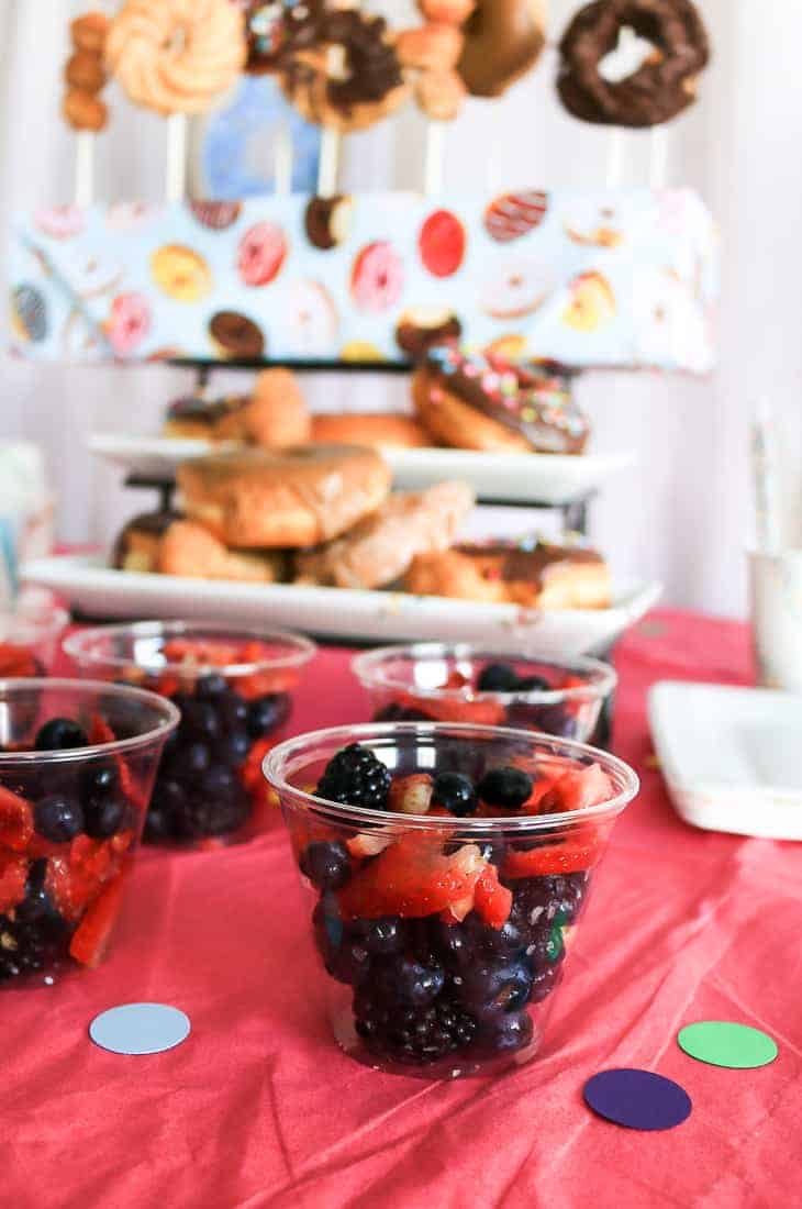 Cups of mixed berries - blueberries, blackberries, and strawberries - served on the dessert table at a donut theme baby shower. 