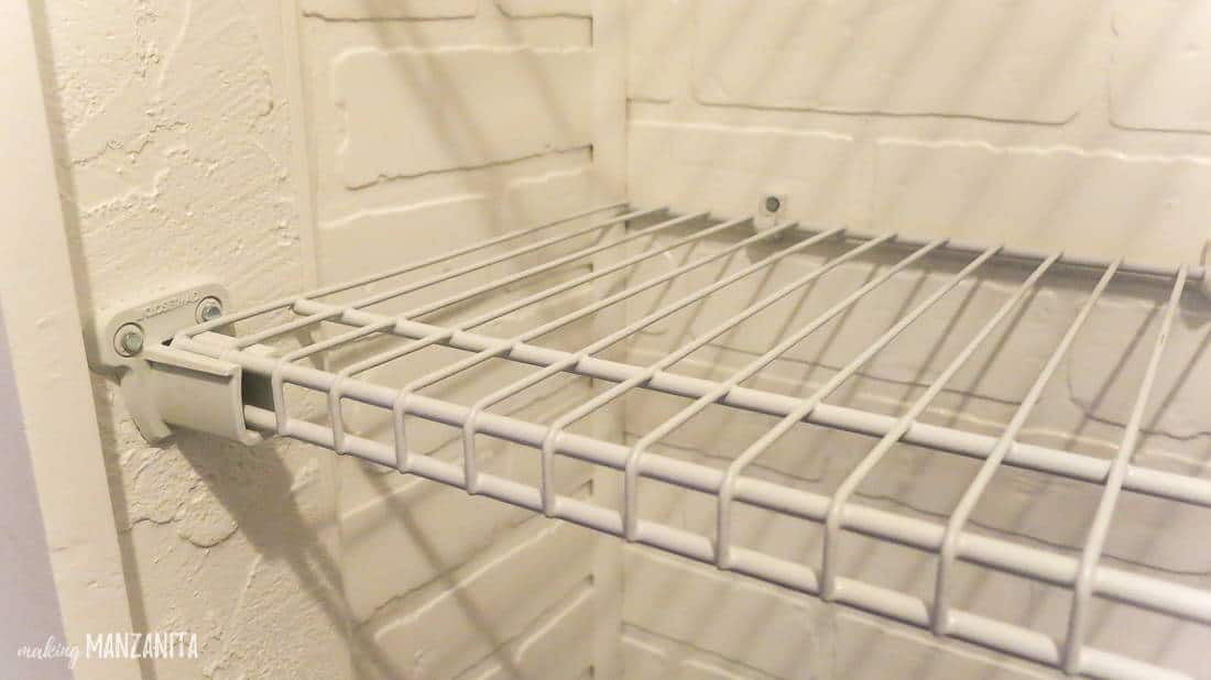 A close up look at the newly installed wire shelving and white faux brick in our home's hallway closet.