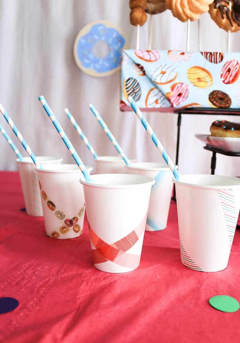 Paper cups with straws lined up, decorated with strips of washi tape.