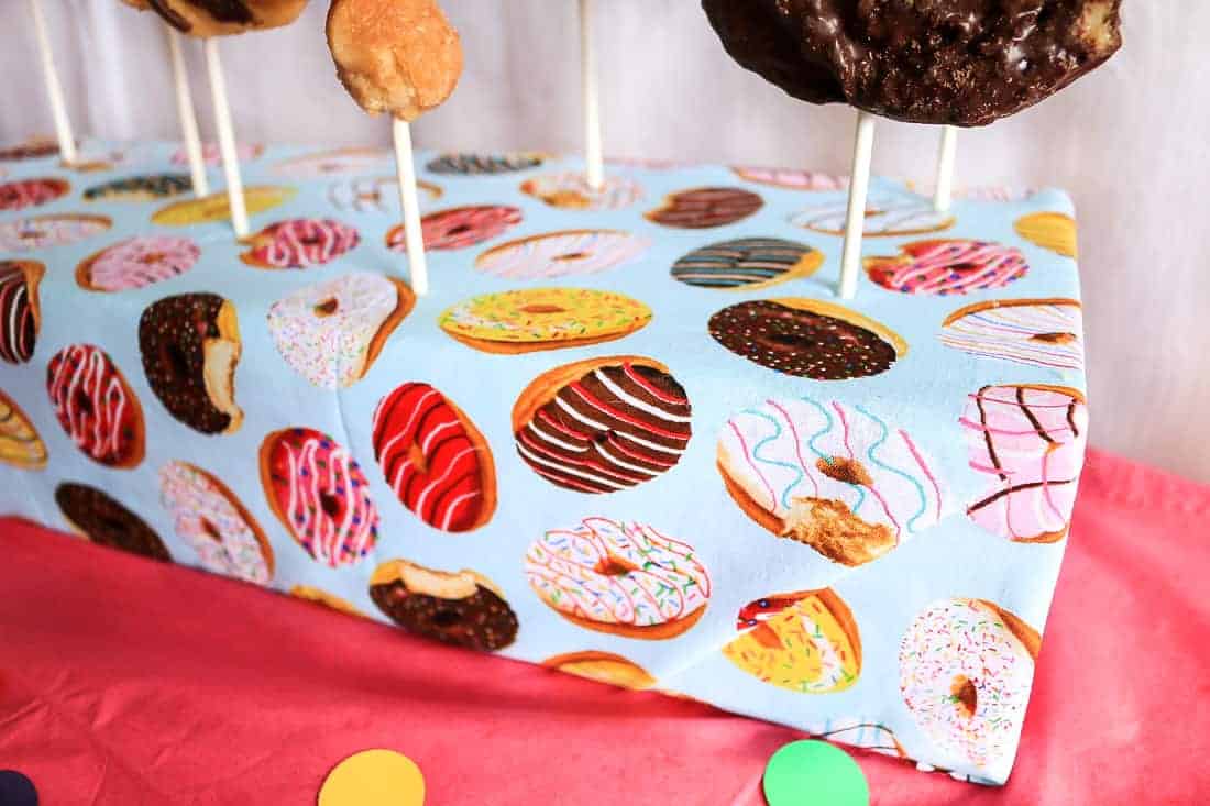 Donuts on stick standing on the finished DIY donut stand with colorful donut printed fabric