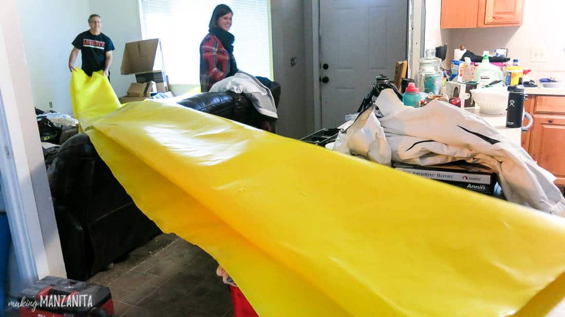 A giant yellow plastic vapor barrier sheet extends through a kitchen into a living room. The vapor barrier will be installed in a crawl space under the home.