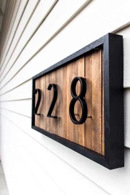 This address sign is made with stained natural wood, a black wood border, and black metal numbers raised slightly off the wood background for added depth.