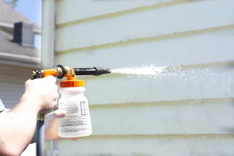 Image of a man with a power wash sprayer washing the exterior siding of a home.