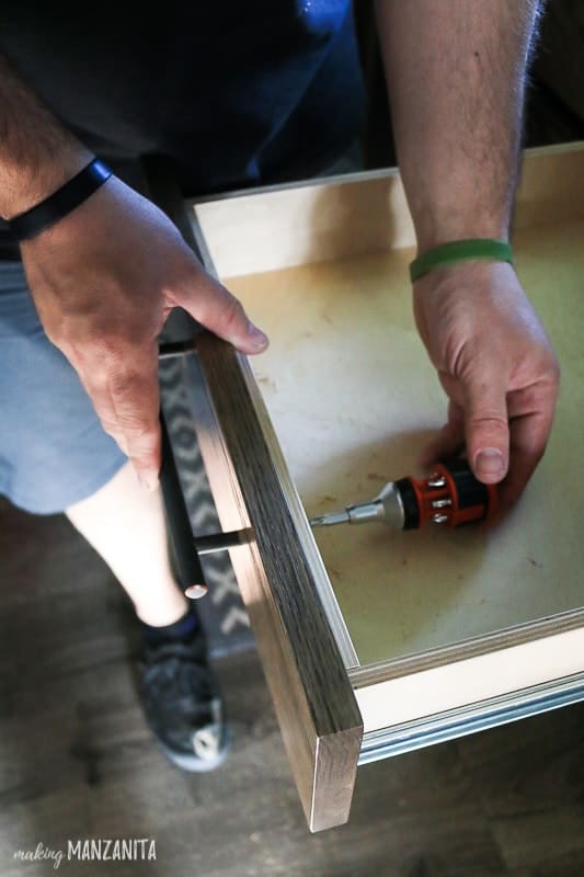 Installing new hardware on our kitchen cabinet drawers, using screws and a drill