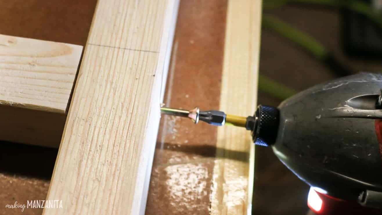 Using a power drill and nails to attach the rungs of the baby blanket ladder.