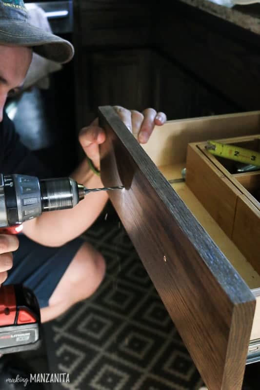 Installing new kitchen hardware on our kitchen drawers using a hand drill