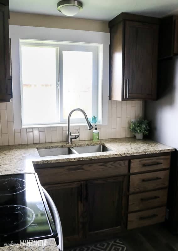 An undermounted sink with granite countertops and dark cabinets.