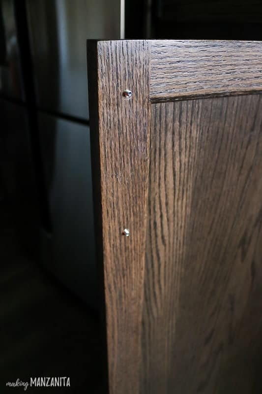 Corner of kitchen cabinet with screws popping through before cabinet handle has been installed