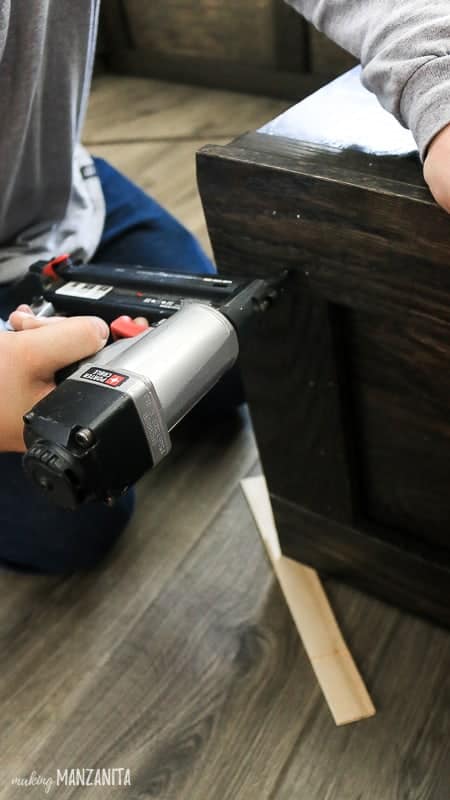 Man nailing trim on booth seating in kitchen