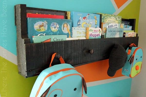 Pallet wood bookshelf hanging on wall with books and backpacks