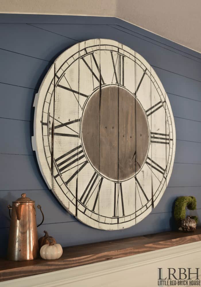 Round clock with roman numerals painted on it hanging on wall
