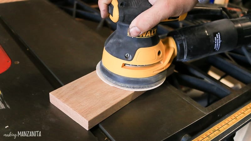 Man holding sander on trim piece