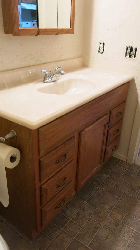 The guest bathroom vanity - wooden drawers and a white resin marble countertop and sink with silver faucet.