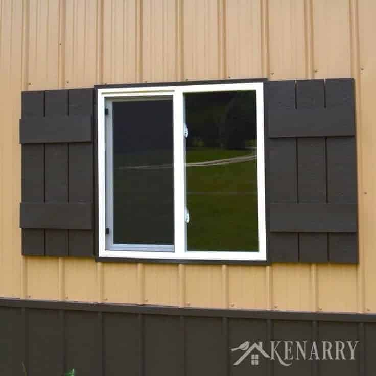 Adding shutters to front-facing windows is a simple way to improve the look of your home. This home features two black farmhouse style shutters on either side of a white framed sliding window.