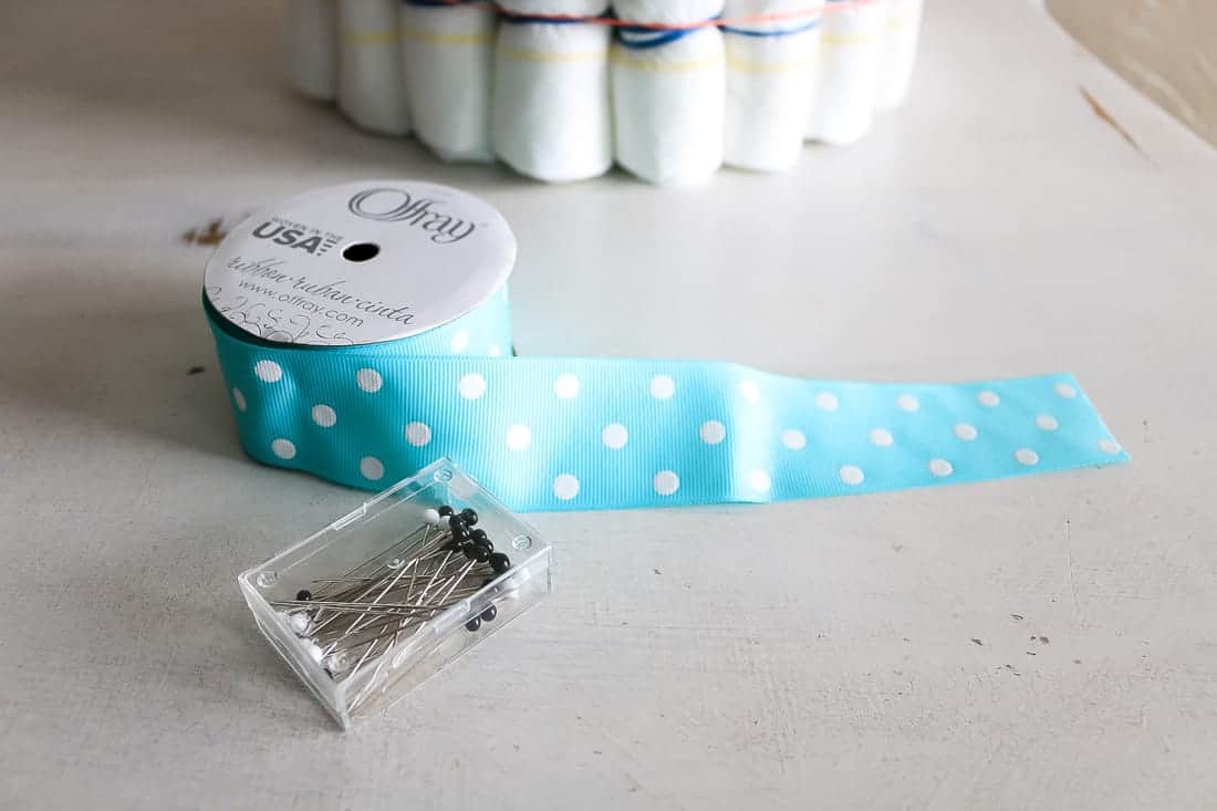 Teal and white polka dot ribbon laying on table with straight pins